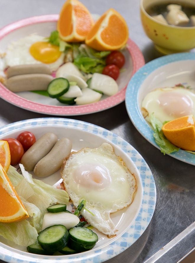 子どもたちが作った料理が皿にもられ、スタッフがゆでたウィンナーとデザートの広島県産清見オレンジが添えられた