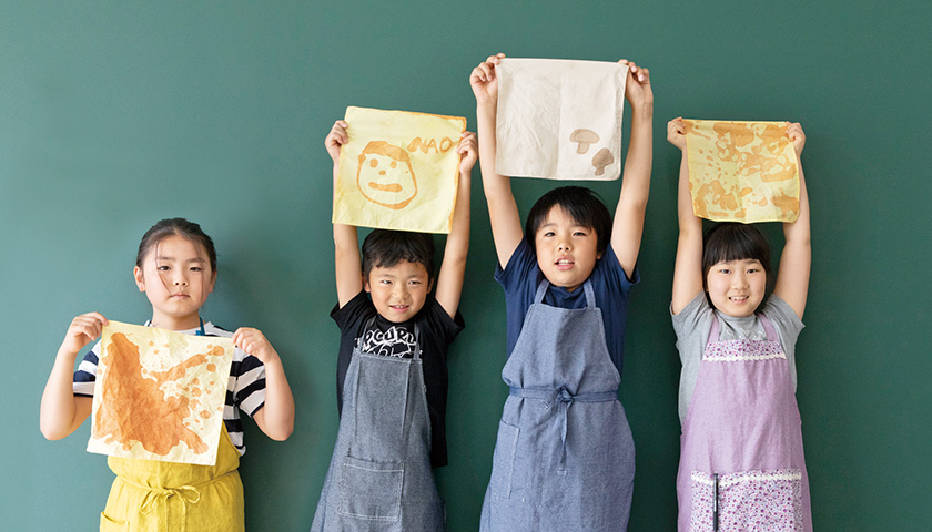 のこり染ワークショップに参加した子どもたちが自分で染めたハンカチを持ってポーズとる様子