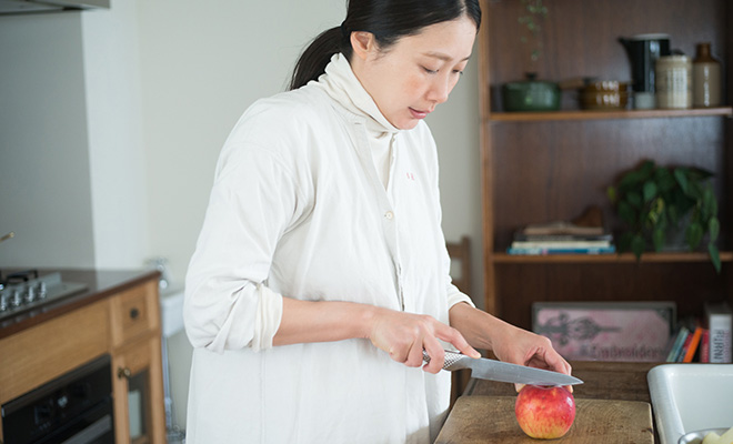 アトリエにて、りんごに包丁を入れようとする長田佳子さん