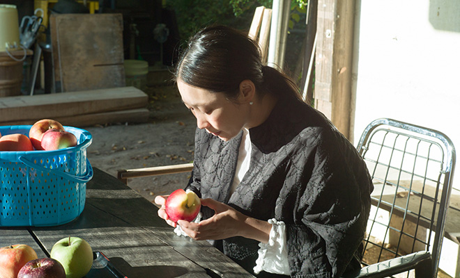 アップルファームさみずで食べ比べたりんごを手に取り見つめる長田佳子さん