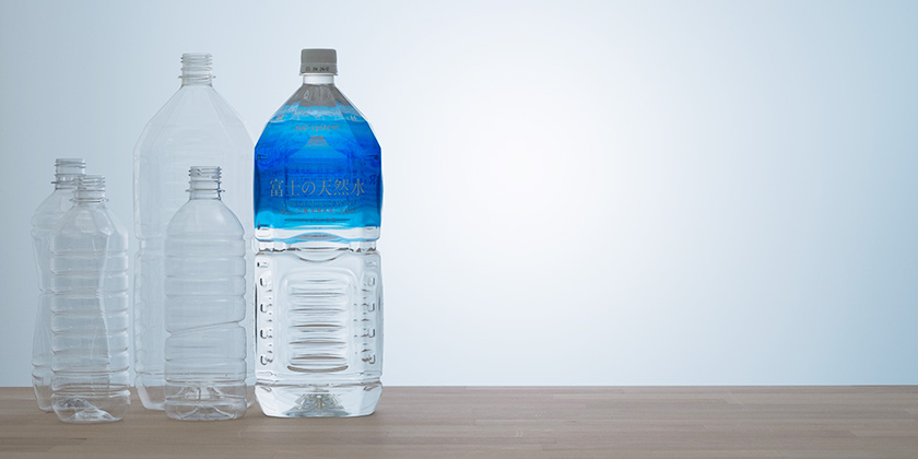 ペットボトル水「富士の天然水」と使用済みペットボトルを圧縮したかたまりがいくつも積み上げられているようす。