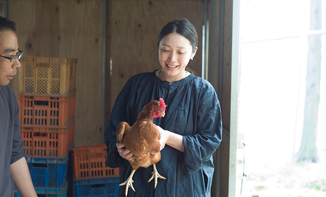 教わったやり方で鶏を抱えて少し緊張した笑顔を見せる長田佳子さん