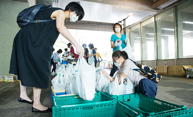 袋に入った食品を手にするボランティアスタッフの女性