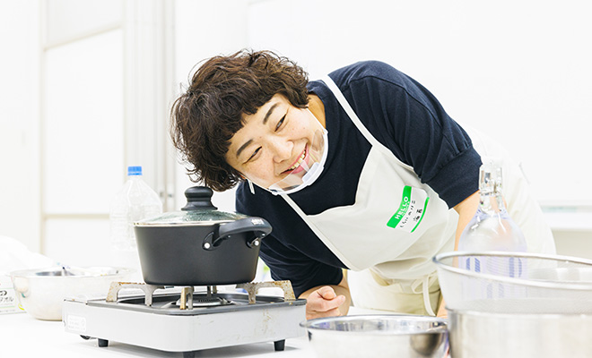 炊飯ワークショップで、ごはんを炊いている鍋に耳を近づけて、炊き上がりの音を確認しているしらいのりこさん