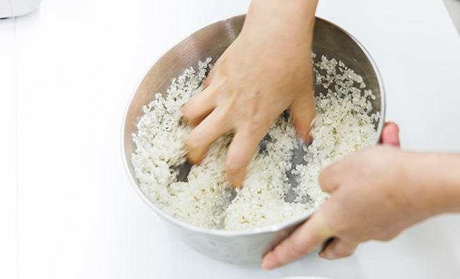 ボウルに入れた米を手で洗っている場面