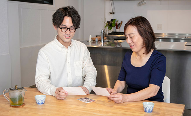 家族写真を手に談笑する上田さん親子