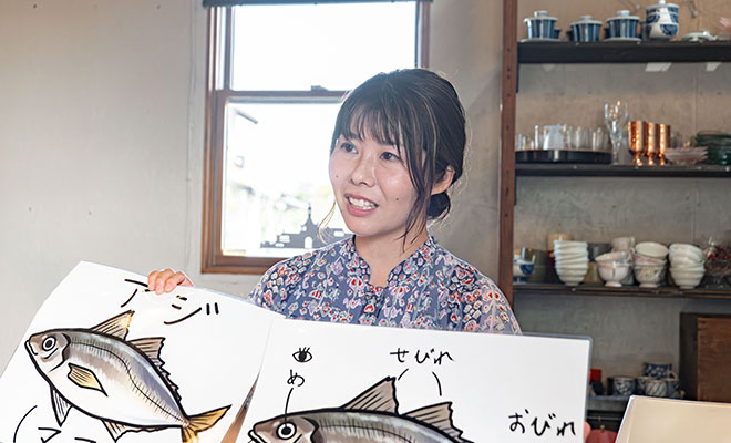 魚のイラストを手に持ってインタビューに答える岩田響子さん