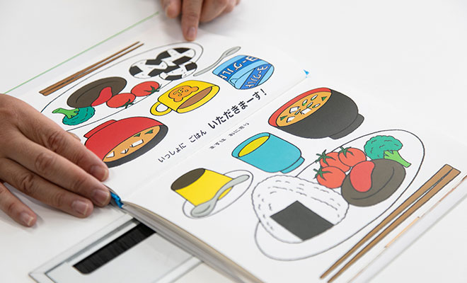 「いっしょにごはん」の絵本を開いているスギヤマさんの手元画像