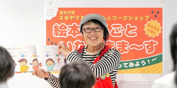 ワークショップで『こえで からだで ゆびもじで やってみよう！あいうえお』（赤ちゃんとママ社、スギヤマカナヨ/作、2024年）を子どもたちと読むスギヤマカナヨさんの画像
