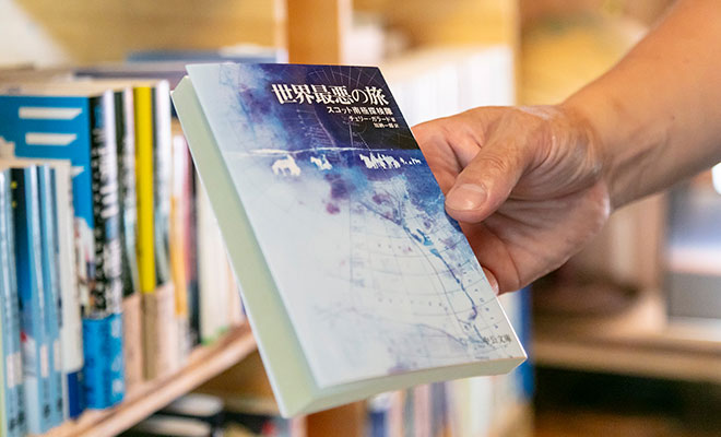 書棚から『世界最悪の旅』を取り出す荻田さんの手元
