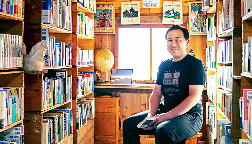 「冒険研究所書店」の店内でイスに座っている荻田泰永さん