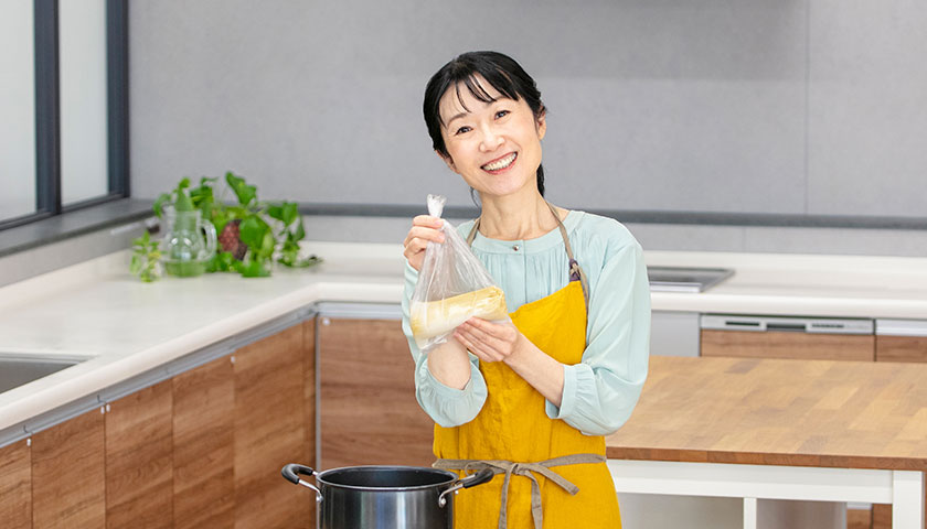防災食のボイル調理をするために鍋の前に立って微笑む今泉マユ子さん