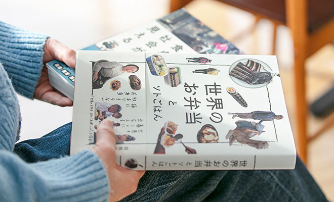 著書『世界の食卓から社会が見える』（大和書房）『世界のお弁当とソトごはん』（三才ブックス）を手に持っている岡根谷さんの手元の画像