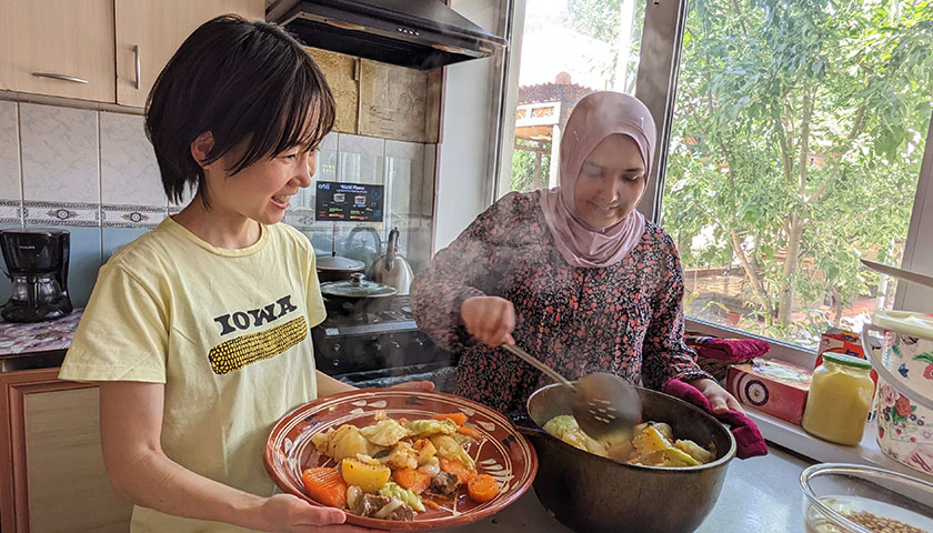 海外の食卓で現地の人と一緒に料理をする岡根谷さん