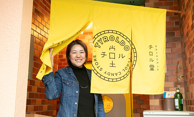 入口のチロル堂ののれんから顔を出す石田さん
