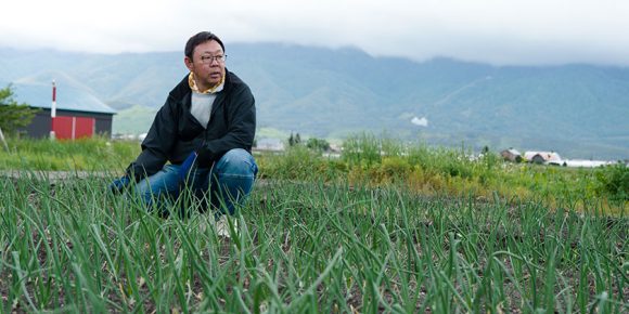 不安そうに畑の作物を眺める村上さん