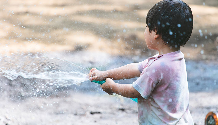 プレーパークでホースから水を出して水遊びしている小さな子ども